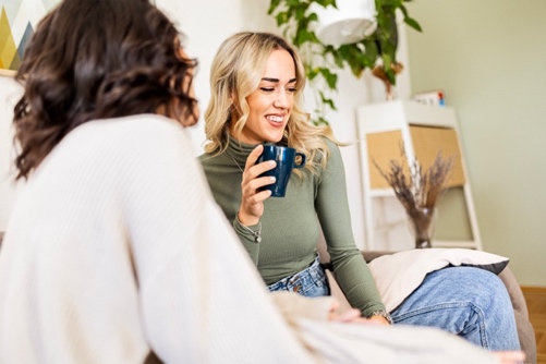 Young women in a comfortable setting laughing and having coffee